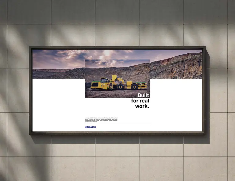 Advertising concept for Komatsu: a billboard reading “Built for real work.” with a yellow loader, on a tiled wall.