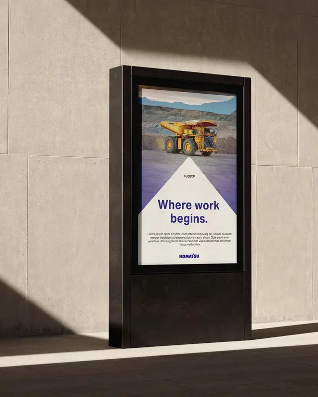 Advertising concept for Komatsu: “Where work begins.” in a city-light display on a sunlit wall.