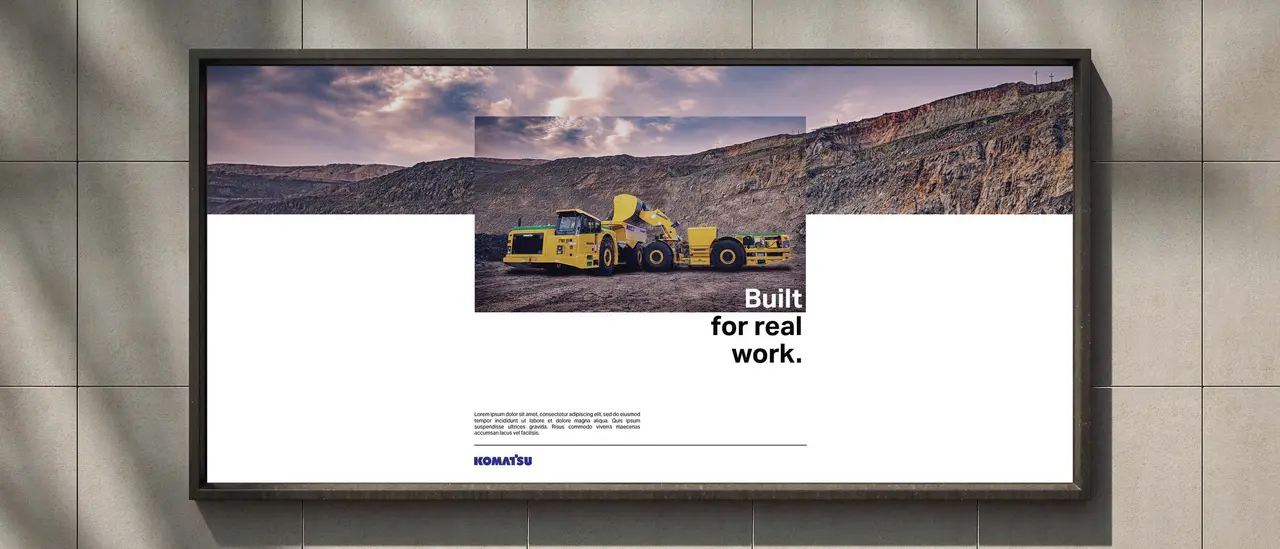 Advertising concept for Komatsu: a billboard reading “Built for real work.” with a yellow loader, on a tiled wall.