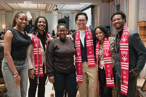 Event photo for the Multicultural Student Center: six people smiling, five in red stoles, at the Student Achievement Gala.