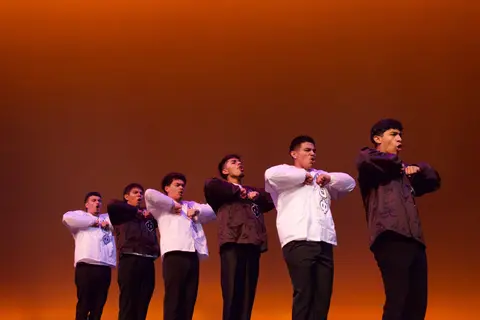 Event photo for the Multicultural Student Center: six performers in white and black on an orange-lit stage at MCOR.