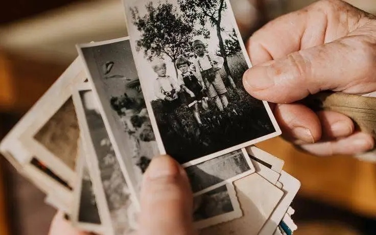 Brand imagery for Reverie Capsule & Co.: hands holding a stack of old black-and-white photographs.