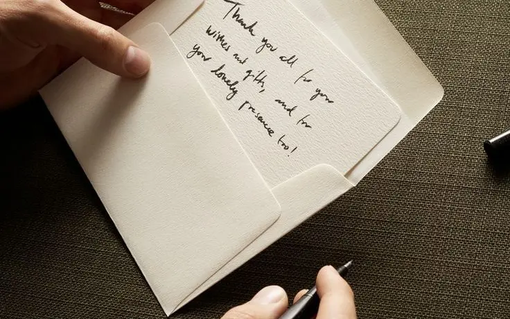 Brand imagery for Reverie Capsule & Co.: hands writing a thank-you note with a pen.