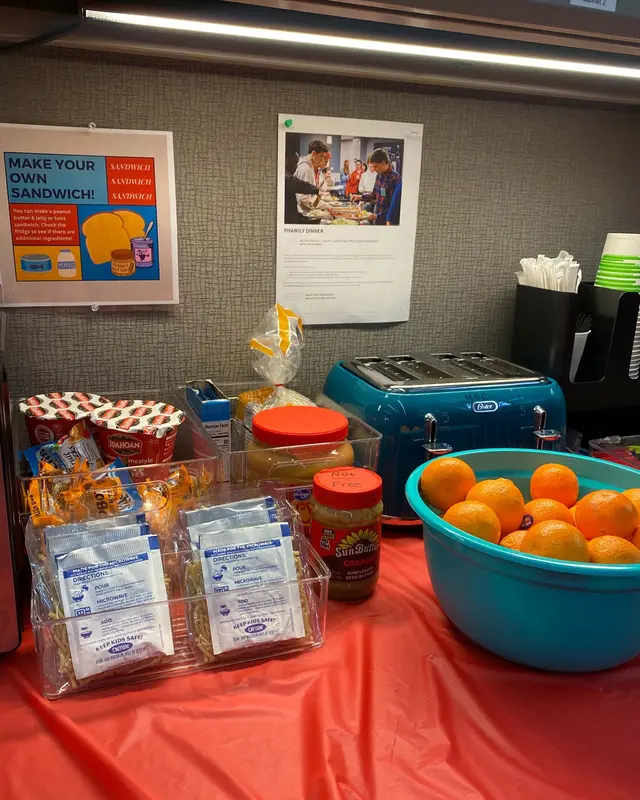 Food donations for Snack n’ Go: oranges, snacks and peanut butter set out on a table by a toaster.